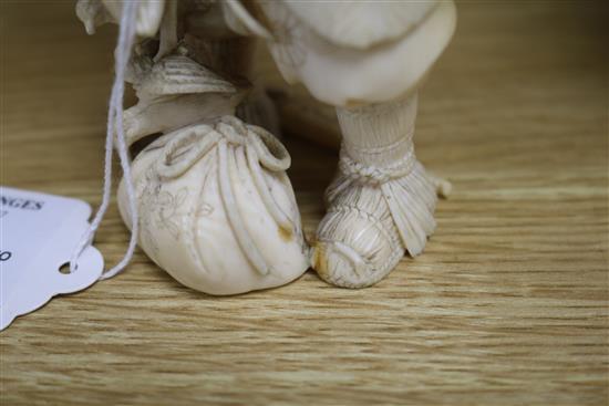 A Japanese carved ivory okimono of a huntsman, Meiji period, holding a hawk and a brace of birds